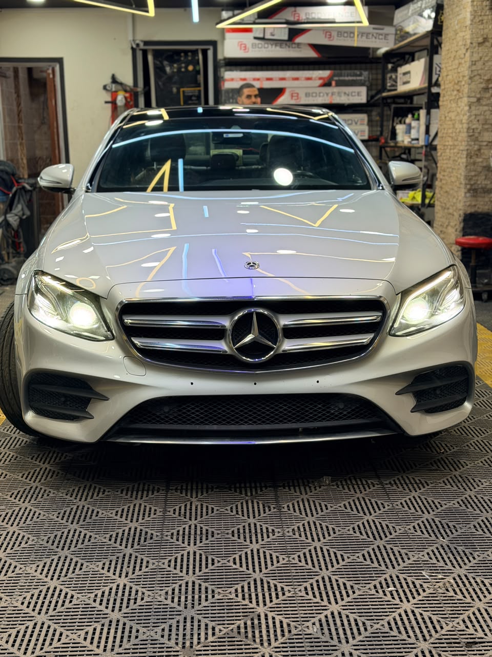 White Mercedes-Benz E-Class AMG Line, front end reflecting the studio lighting