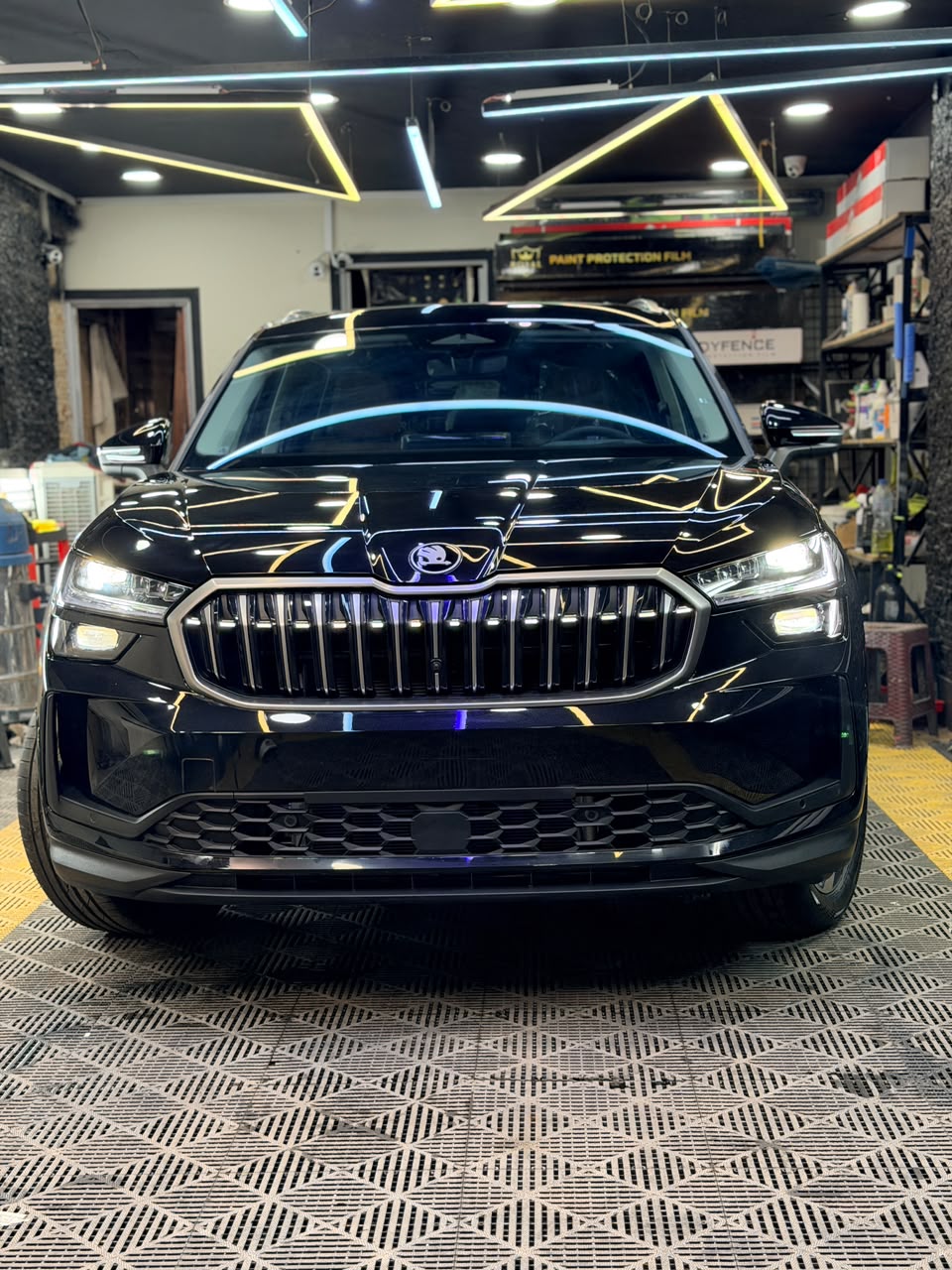 Black Škoda Kodiaq with the illuminated grille lit up, seen head-on